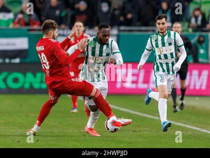 BUDAPEST, UNGARN - 6. MÄRZ: Herdi Prenga von Kisvarda meistert gute Herausforderungen Franck Boli von Ferencvarosi TC neben Zeljko Gavric von Ferencvarosi TC während des ungarischen OTP Bank Liga Spiels zwischen Ferencvarosi TC und Kisvarda Master Good am 6. März 2022 in der Groupama Arena in Budapest, Ungarn. Stockfoto