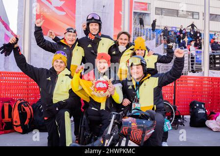 Peking, China. 07. März 2022. Paralympics, para Alpine Skiing, Frauen, kombiniert, sitzen, Im Nationalen Alpinen Skizentrum: Anna-Lena Forster aus Deutschland (M) freut sich über ihren ersten Platz mit Leander Kress (l) aus Deutschland Justus Wolf (r), Nationaltrainer, und anderen Teammitgliedern. Quelle: Christoph Soeder/dpa/Alamy Live News Stockfoto