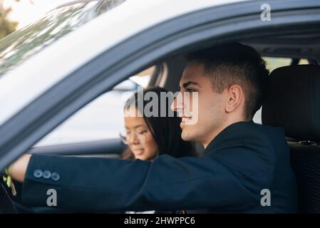 Lächelnder Geschäftsmann mit einem Kollegen im Auto Stockfoto