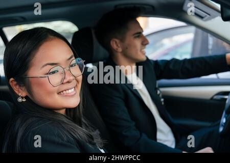 Lächelnde Geschäftsfrau mit Kollegen beim Autofahren Stockfoto