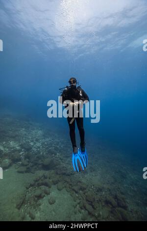 Junger Mann mit Tauchausrüstung unter Wasser Stockfoto