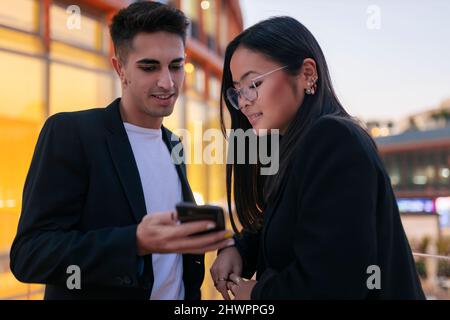 Geschäftsmann, der einer Geschäftsfrau in der Stadt ein Smartphone zeigt Stockfoto