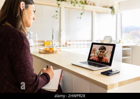 Geschäftsfrau, die zu Hause mit einem Kollegen auf einem Laptop einen Videoanruf führt Stockfoto