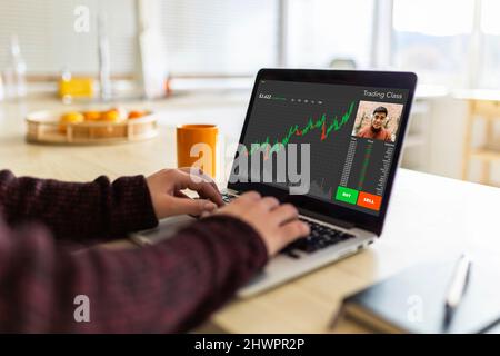 Eine Geschäftsfrau, die mit einem Laptop handelt und Videoanruf mit einem Kollegen zu Hause führt Stockfoto