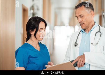Krankenschwester und Arzt diskutieren über Krankenakte im Krankenhaus Stockfoto
