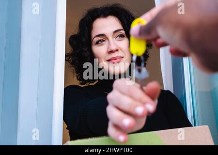 Lächelnde Frau, die Schlüssel von der immobilienmaklerin im neuen Haus nimmt Stockfoto