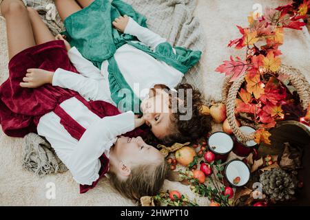 Lächelnde Mädchen, die beim Picknick im Wald an Früchten auf der Decke liegen Stockfoto