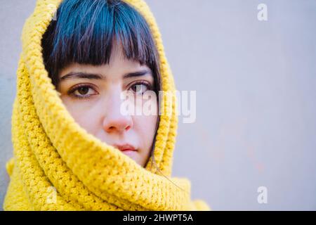 Schöne junge Frau mit Pony in gelben Schal gewickelt Stockfoto