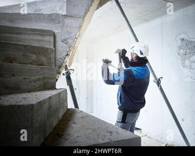 Arbeiter, der Rohre von Betontreppen auf der Baustelle entfernt Stockfoto