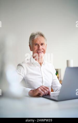 Geschäftsmann mit Laptop am Schreibtisch im Studio Stockfoto