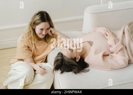 Lächelnde Tochter, die Mutter auf dem Bett liegend ansieht Stockfoto
