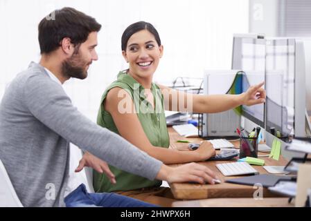 Sie hat einige tolle Ideen für das Projekt. Aufnahme einer jungen Geschäftsfrau, die ihrem Kollegen am Computer etwas zeigt. Stockfoto