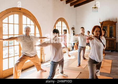 Multirassische Freunde üben ihre Kriegerposition im Yoga-Studio Stockfoto