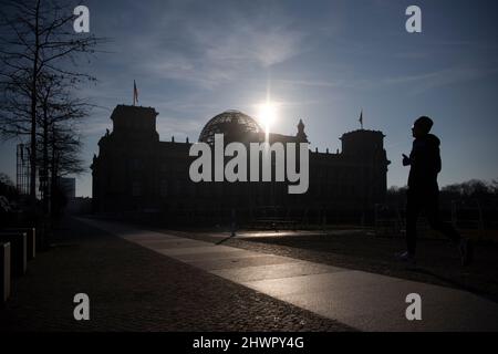 Berlin, Deutschland. 07. März 2022. Im Gegenlicht der Sonne kann der Reichstag nur als Silhouette gesehen werden. Quelle: Paul Zinken/dpa/Alamy Live News Stockfoto