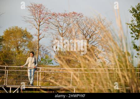 Eine junge Frau steht auf der Fußgängerbrücke über einen Fluss namens Manooni in Sidhpur, Himachal Pradesh Stockfoto