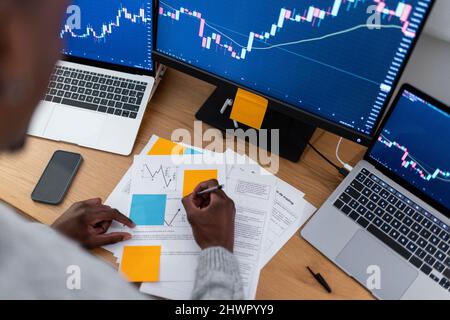 Junge Trader, die Strategien auf Papier machen, arbeiten spät in der Nacht im Home Office Stockfoto