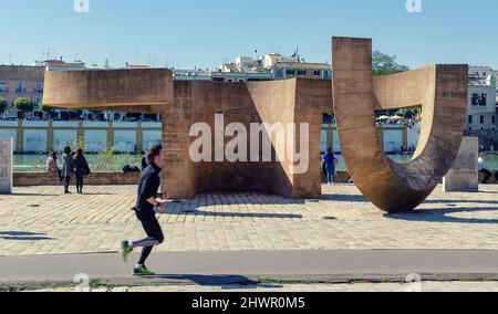 Denkmal der Toleranz des Bildhauers Eduardo Chillida am Guadalquivir. Mann läuft und Leute genießen einen sonnigen Tag. Stockfoto