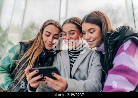 Lächelnde junge Freunde, die Smartphone schauen Stockfoto