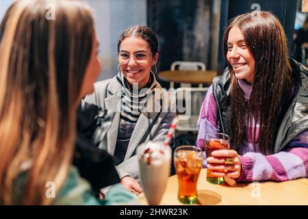 Lächelnde Frauen, die im Café mit einer jungen Freundin sprechen Stockfoto