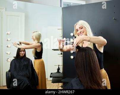 Lächelnder Friseur schneidet den Kunden die Haare im Salon Stockfoto