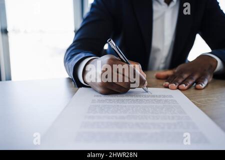 Kunde unterzeichnet Vertrag am Tisch im Büro Stockfoto