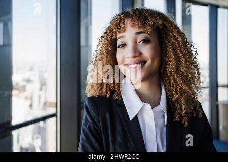 Glückliche Geschäftsfrau mit lockigen Haaren im Büro Stockfoto