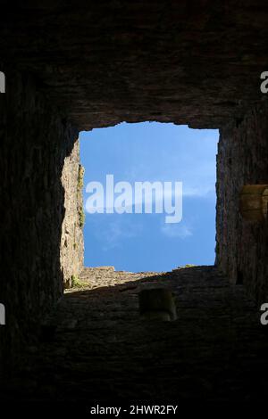 Blick auf den blauen Himmel durch das Fenster, das sich in einer alten Burgmauer öffnet Stockfoto