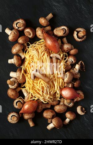 Studioaufnahme von rohen Zwiebeln, Pilzen und fettuccine Pasta Stockfoto