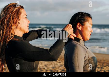 Frau, die Surferin beim Anziehen von Neoprenanzüge am Strand, Gran Canaria, Kanarische Inseln, unterstützt Stockfoto