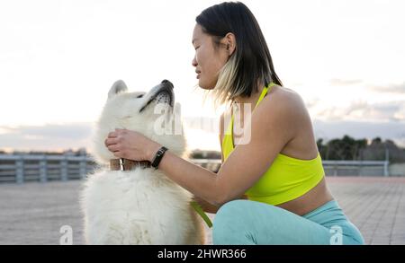 Junge Frau streichelte Akita Hund auf dem Fußweg Stockfoto