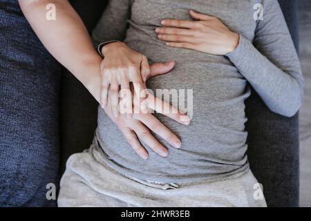 Mann, der zu Hause den Magen einer Schwangeren berührt Stockfoto