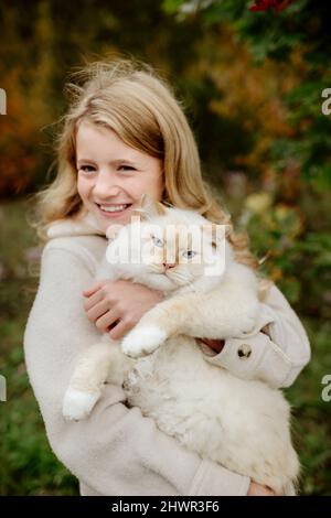 Happy blonde Mädchen mit Ragdoll Katze im Garten Stockfoto