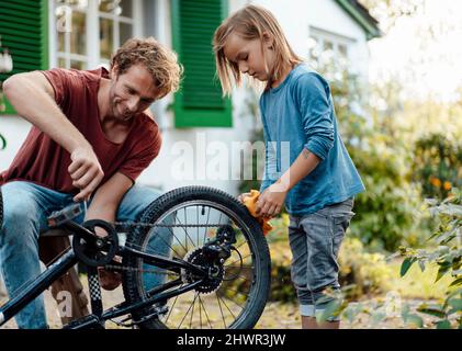 Vater hilft Sohn Reparatur Fahrrad im Hinterhof Stockfoto