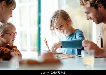 Eltern und Schwester schauen sich den Jungen an, der zu Hause Mikado spielt Stockfoto