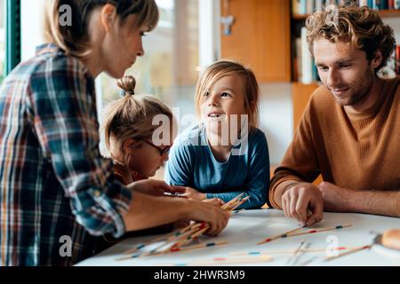 Eltern mit zwei Kindern spielen zu Hause Mikado Stockfoto