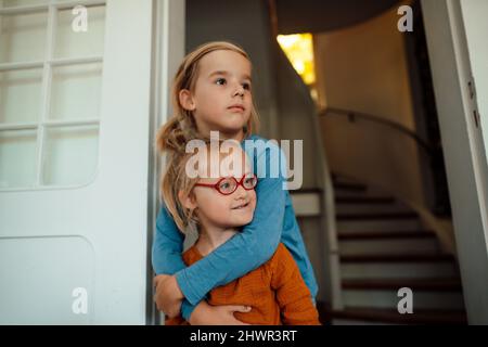 Nachdenklicher Bruder umarmt Schwester am Eingang Stockfoto