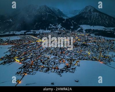 Deutschland, Bayern, Oberstdorf, Hubschrauberansicht der schneebedeckten Stadt in den Allgauer Alpen bei Dämmerung Stockfoto
