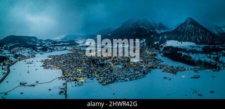 Deutschland, Bayern, Oberstdorf, Helikopter-Panorama der schneebedeckten Stadt in den Allgauer Alpen bei Dämmerung Stockfoto