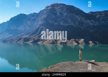 Eine Frau, die den Bergsee von der nahegelegenen Kante aus bewundert Stockfoto