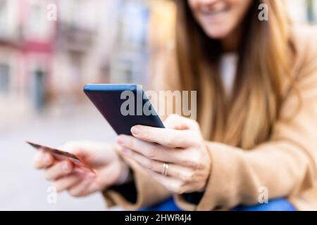 Frau mit Debitkarte, die online über das Smartphone bezahlt Stockfoto