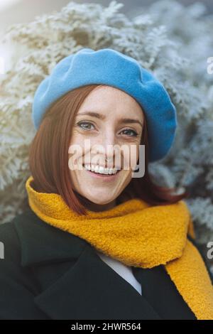 Glücklich schöne Rothaarige Frau trägt gelben Schal und blaue Baskenmütze Stockfoto