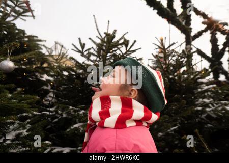 Mädchen, die vor dem Weihnachtsbaum die Zunge herausstreckt Stockfoto