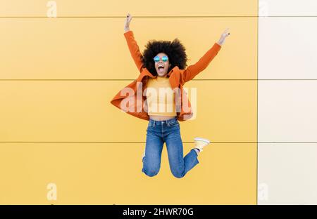 Glückliche Frau, die vor der Wand springt Stockfoto