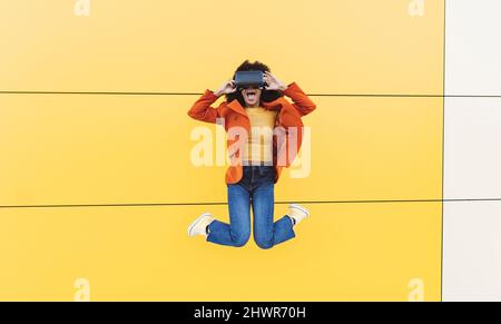 Fröhliche Frau in VR-Brille und springt vor die Wand Stockfoto
