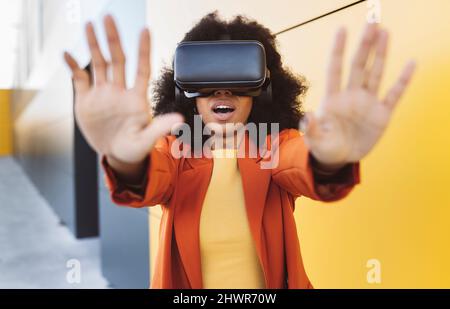 Frau mit VR-Brille tut Stop-Geste in der Nähe der Wand Stockfoto