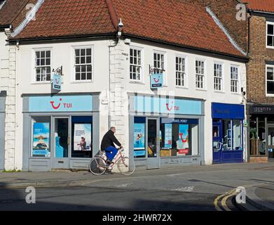 Mann, der an einer Niederlassung des TUI-Reisebüros in Selby, North Yorkshire, England, vorbeiradelt Stockfoto