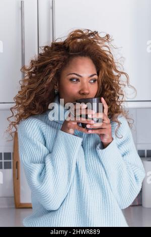 Junge Frau trinkt Kaffee zu Hause Stockfoto