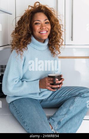 Glückliche Frau mit Kaffeetasse in der Küche Stockfoto