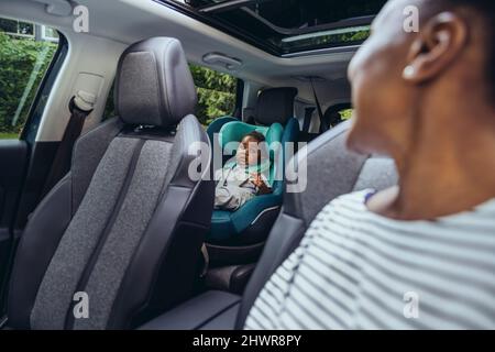 Mutter schaut auf den kleinen Jungen, der im Auto sitzt Stockfoto