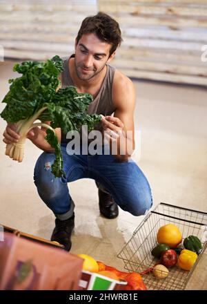 Ich kaufe nur das frischeste. Aufnahme eines jungen Mannes, der den Spinatkopf zum Kauf auswählt. Stockfoto